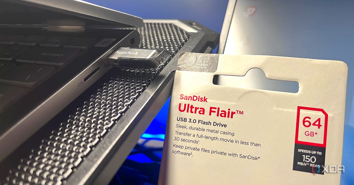 A SanDisk USB 3.0 flash drive is connected to a laptop beside its retail packaging.
