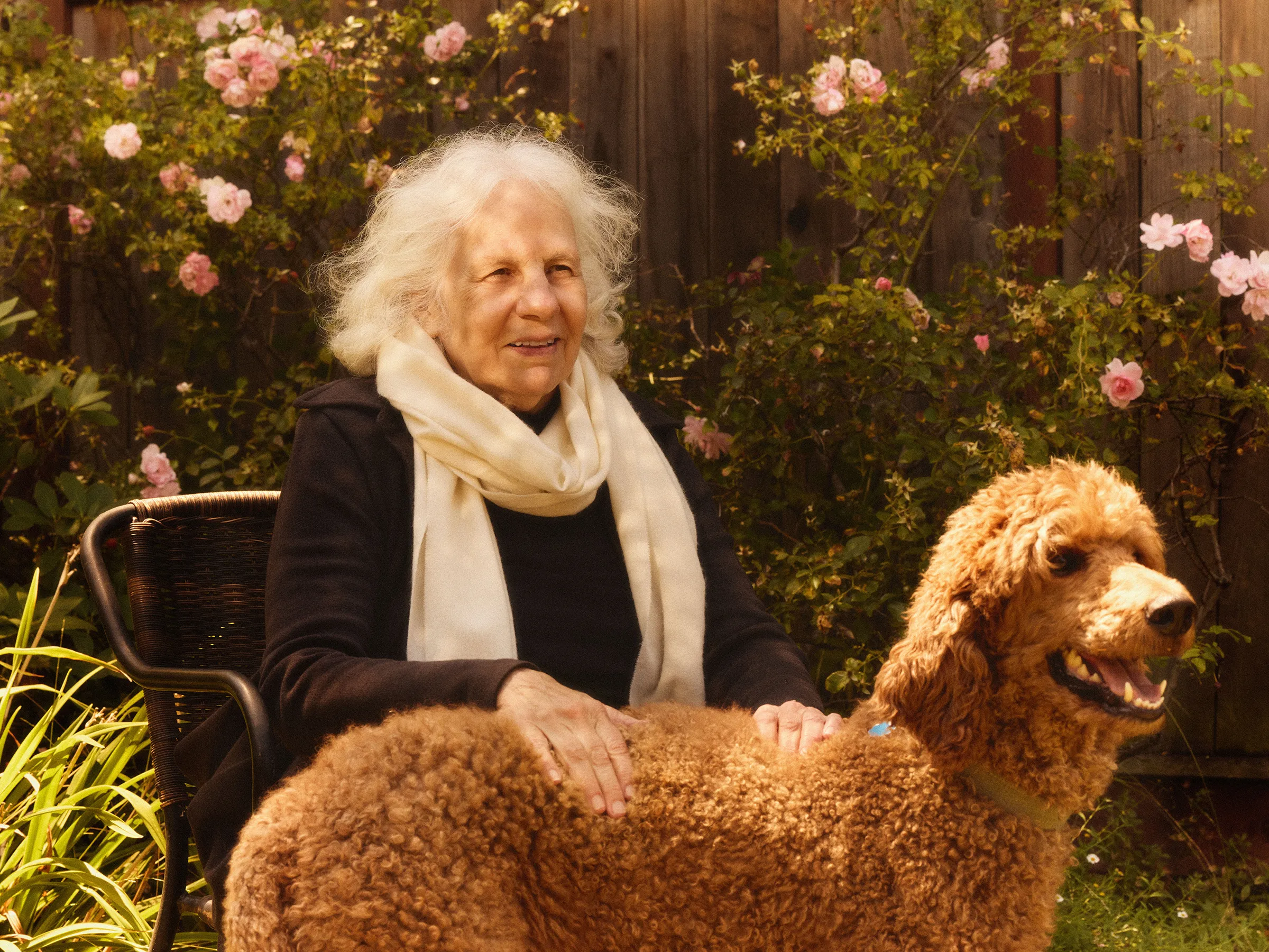 Paulina Borsook sits outdoors beside a goldendoodle.