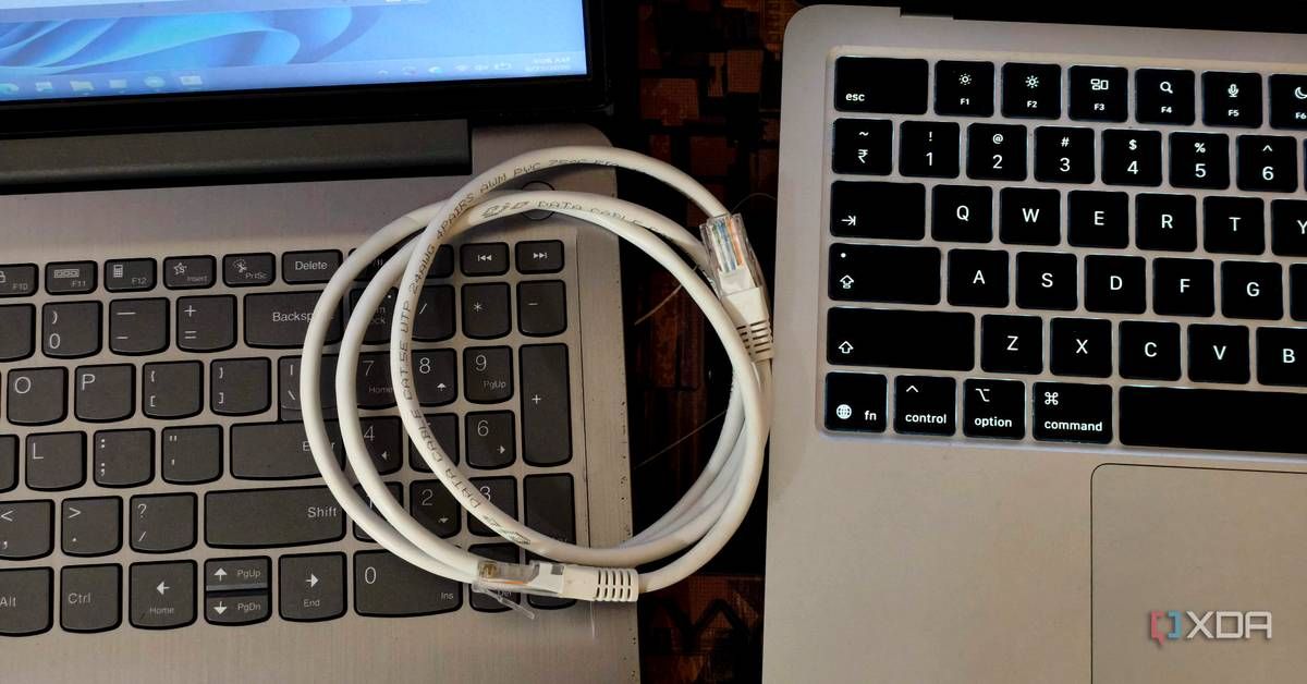 An Ethernet cable lies across the keyboards of two laptop computers.