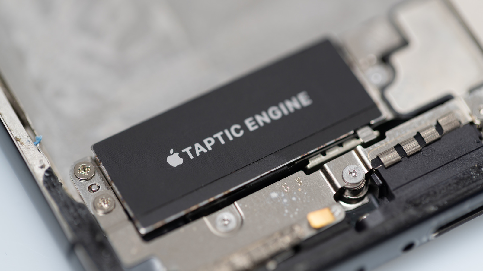 The inside of an iPhone with its black Taptic Engine module visible.