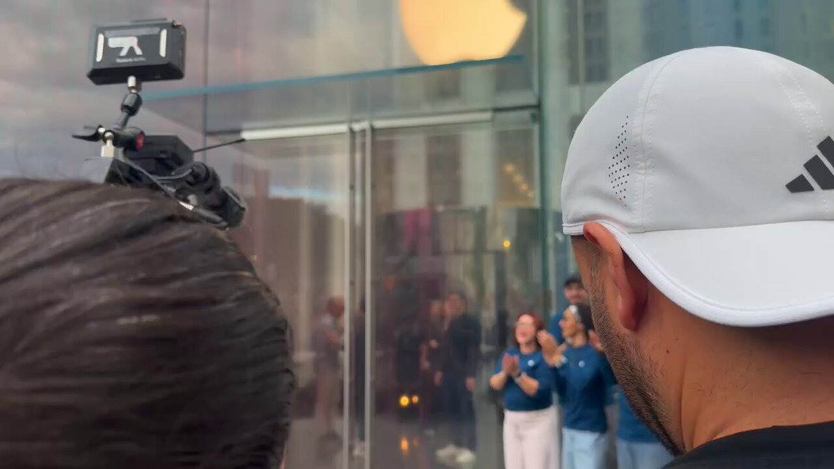 People and cameras gather outside the glass entrance of Apple Fifth Avenue on iPhone 18 Pro launch day.