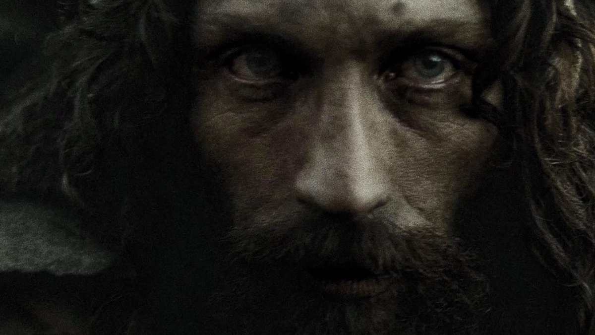 A bearded man in a fur hood stares into the camera in a dark still from Werwulf.