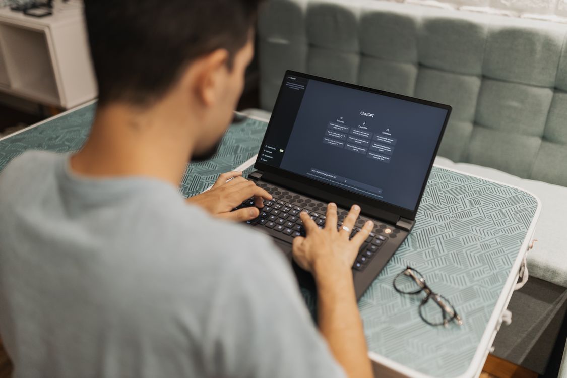 Person using a laptop with the ChatGPT interface visible on its screen.