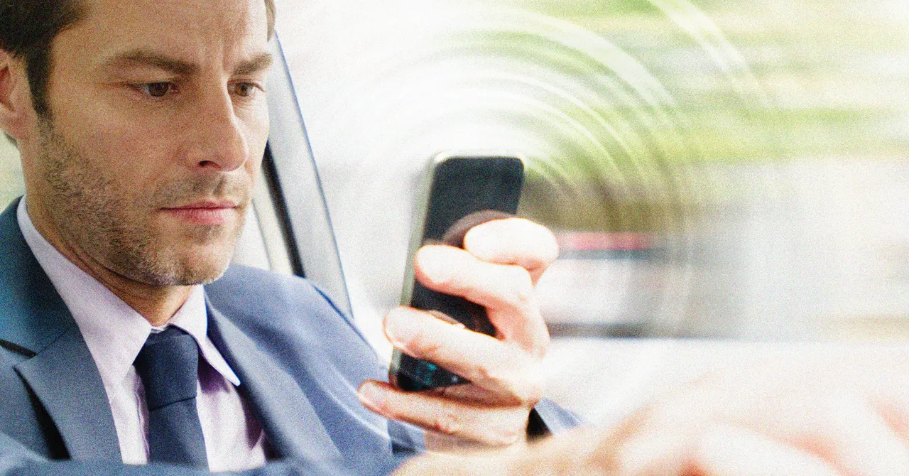 A person holding a smartphone while looking away from the screen.