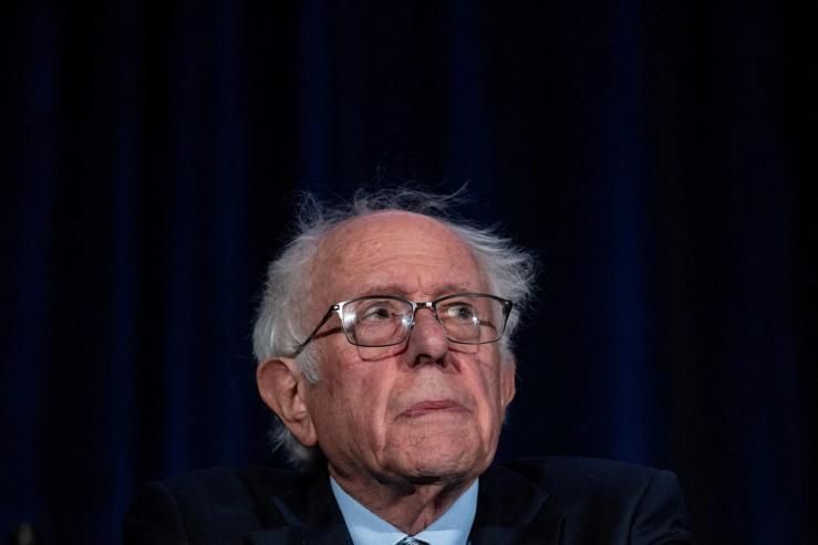 Sen. Bernie Sanders seated against a dark blue background.