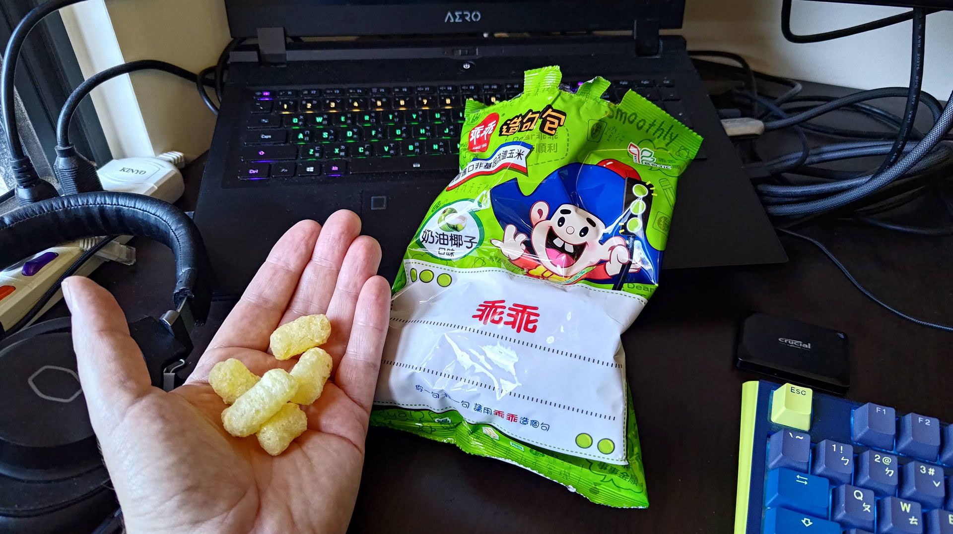 Green bags of Guai Guai snacks displayed beside computing equipment.